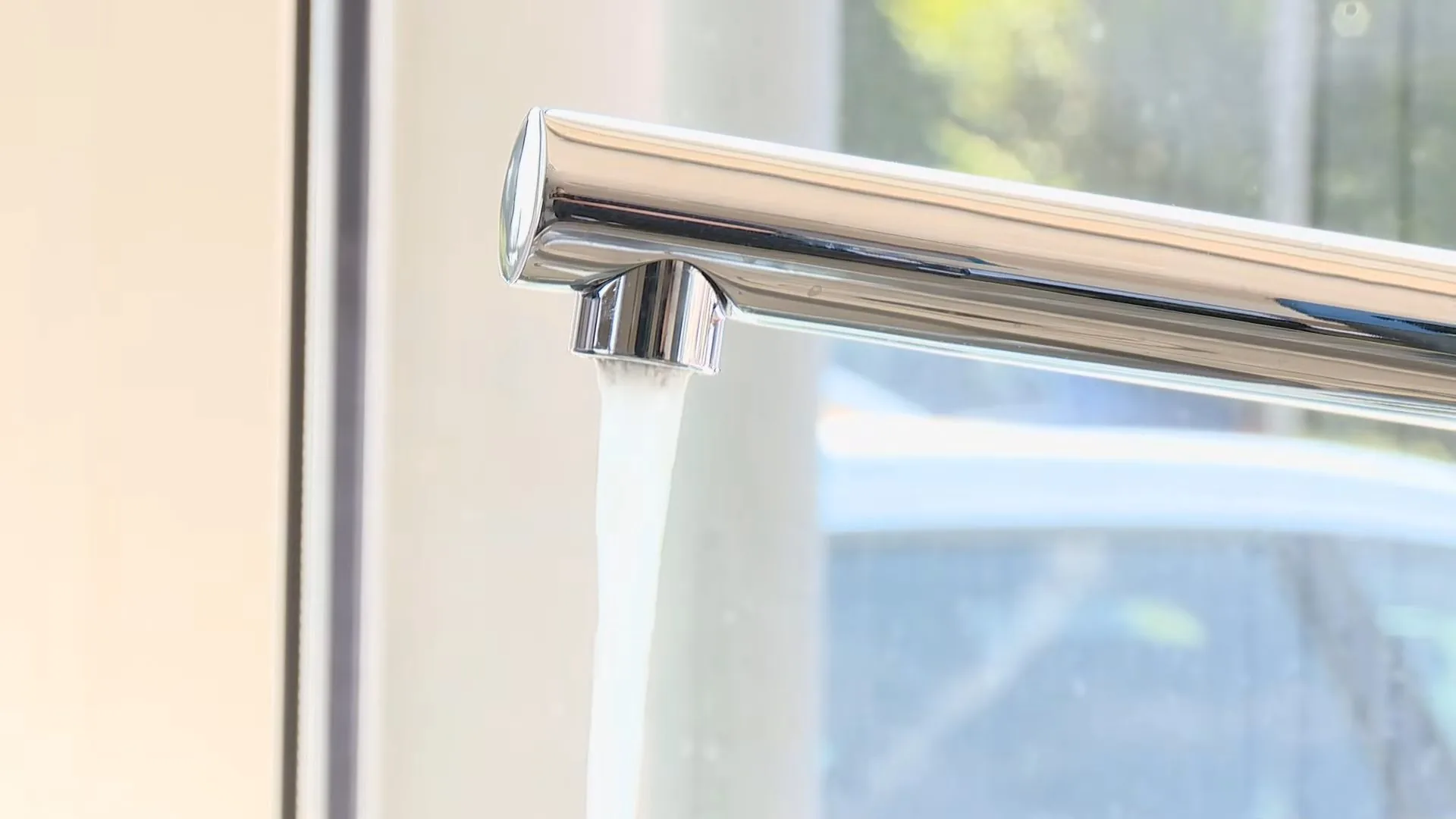 Chrome faucet with a clear stream of water running from its aerator.