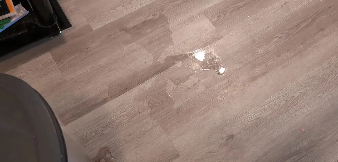 Single water droplet on a wood-look plank floor.